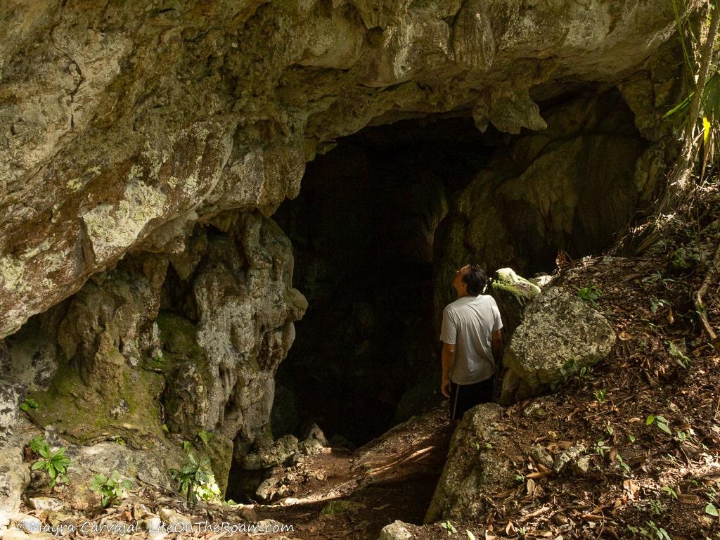 A man standing at the entrance of an underground cave