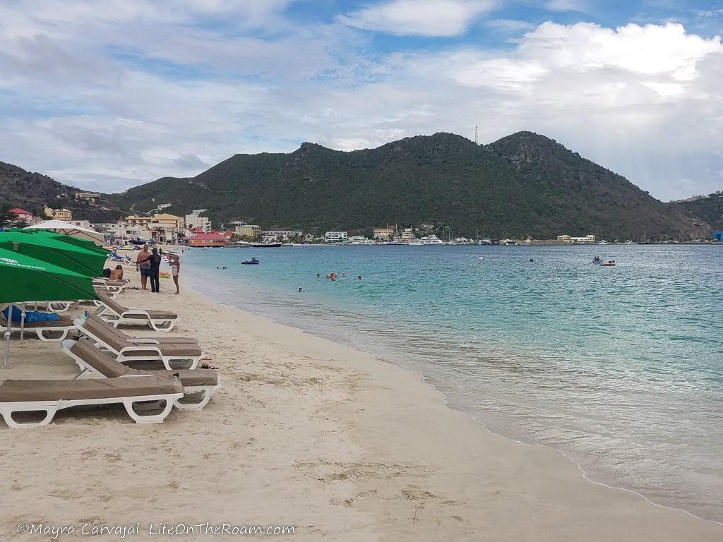 Beach chairs along a sandy beach and hills in the background