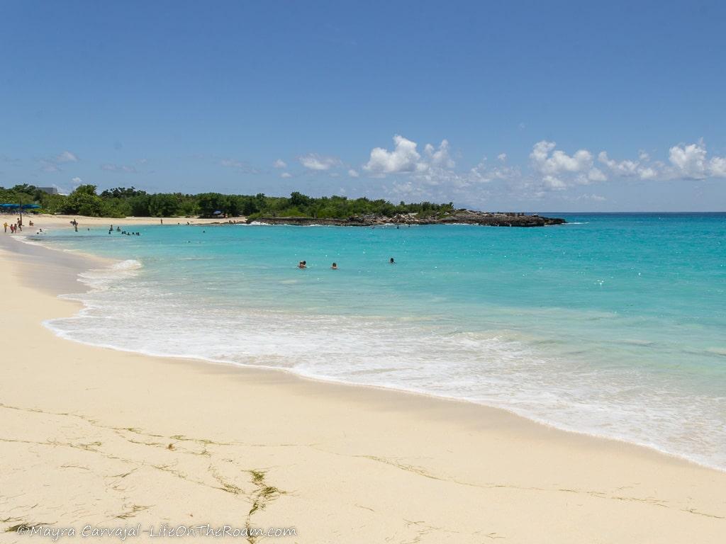 A sandy beach with turquoise waters in a sunny day
