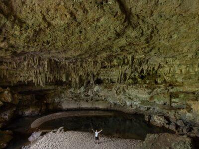 A man standing at the centre of a cave with high arched ceiling with stalactites