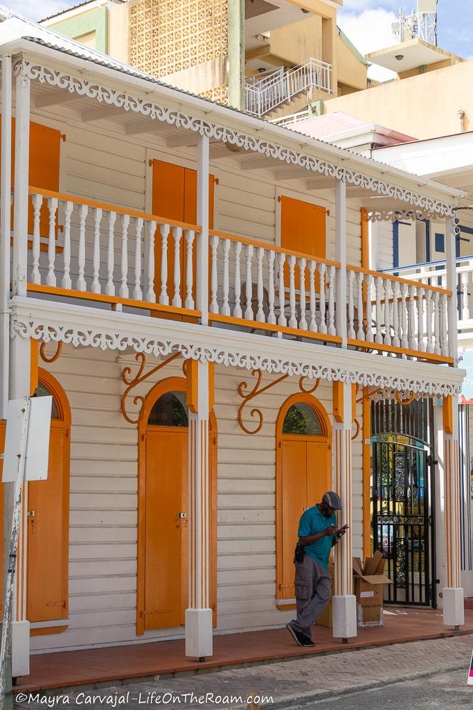 A traditional two-storey white house in the Caribbean with a porch and yellow doors and windows