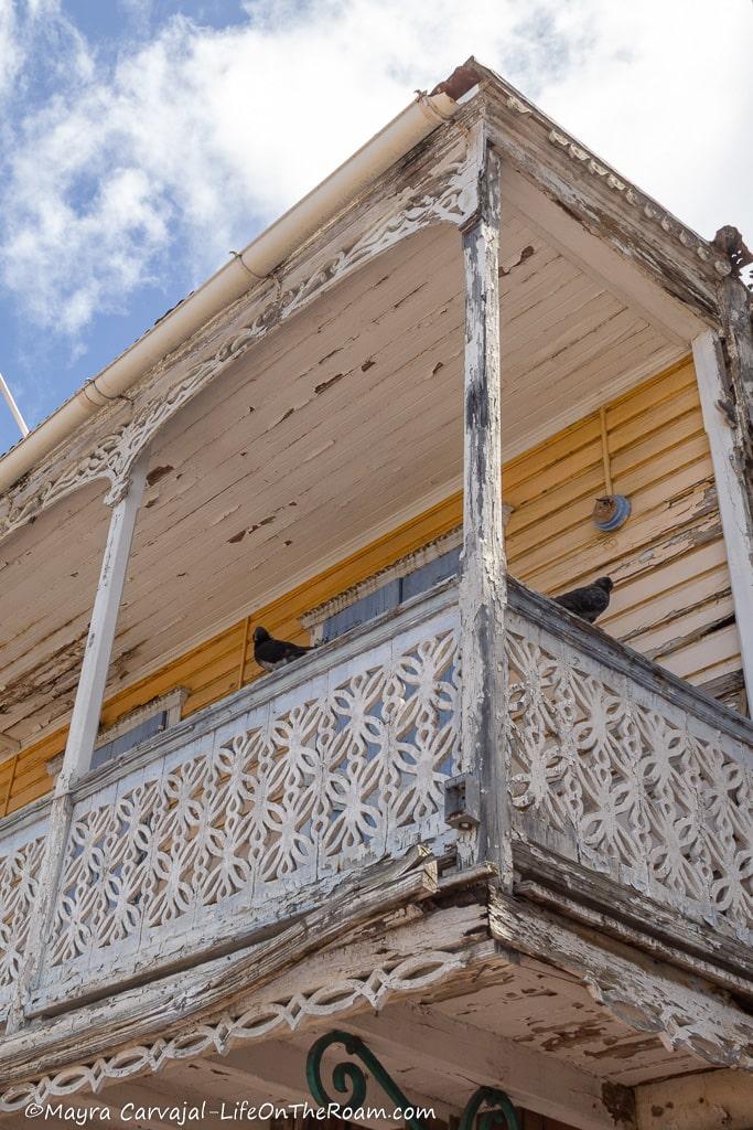 The porch of a traditional Caribbean house with yellow walls and intricate wood lattice