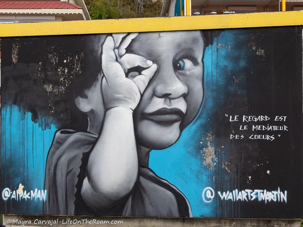 Mural of a smiling black toddler with blue eyes and the text "Le regard est le mediateur du coeur"