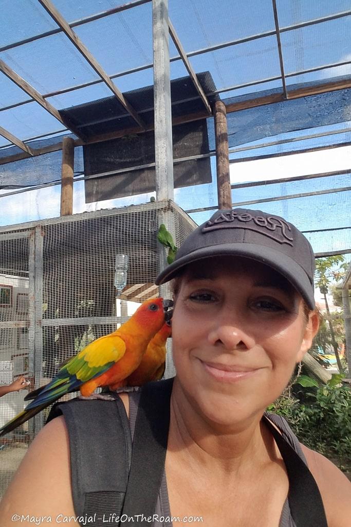 Mayra with a colourful parakeet on her shoulder