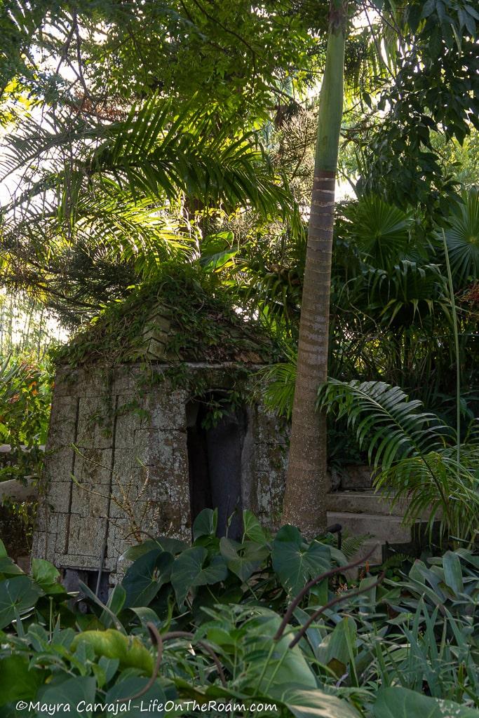 A stone pavilion in a lush  green landscape