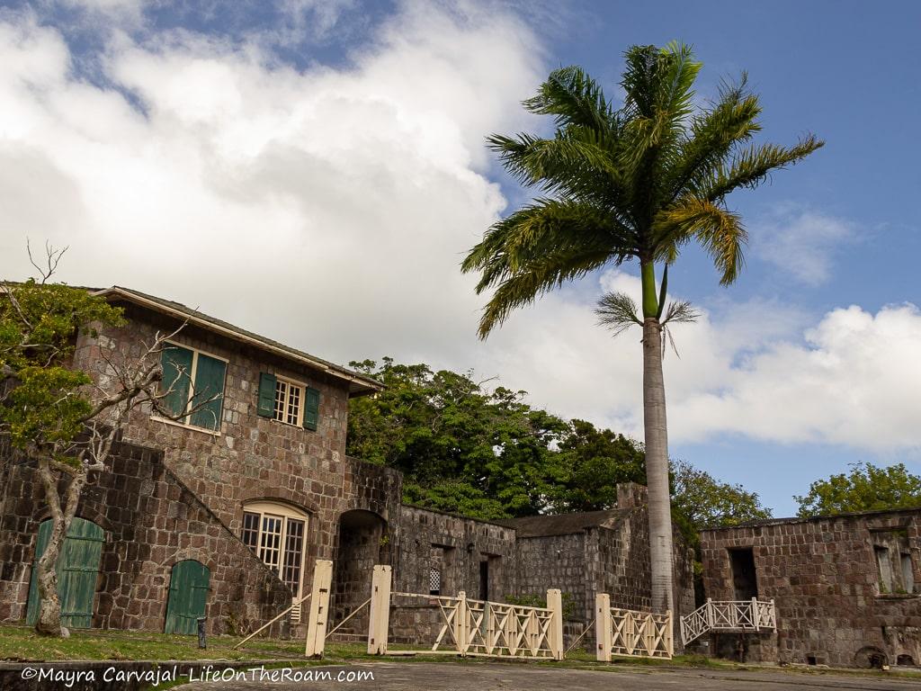 An abandoned 2-storey stone building with palm trees