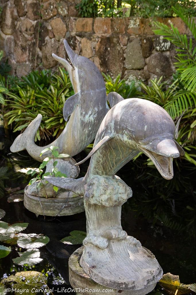 A sculpture of two dolphins jumping on a pond