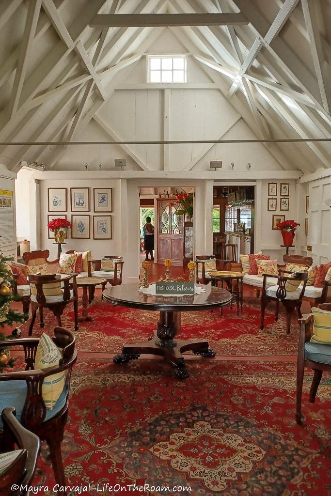 A lounge room with red rugs, white walls, tall ceilings and period furniture