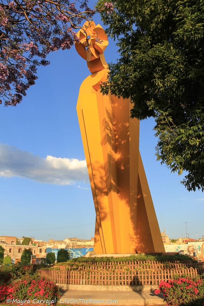 A tall iron yellow sculpture in a park