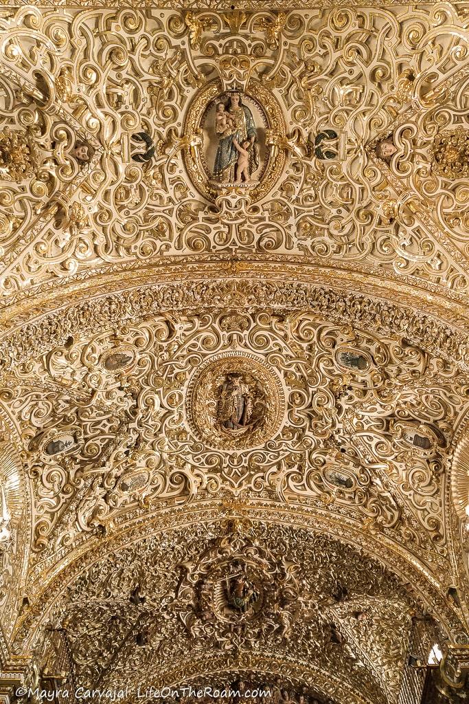 An arched ceiling in a church, with swirls and three medallions