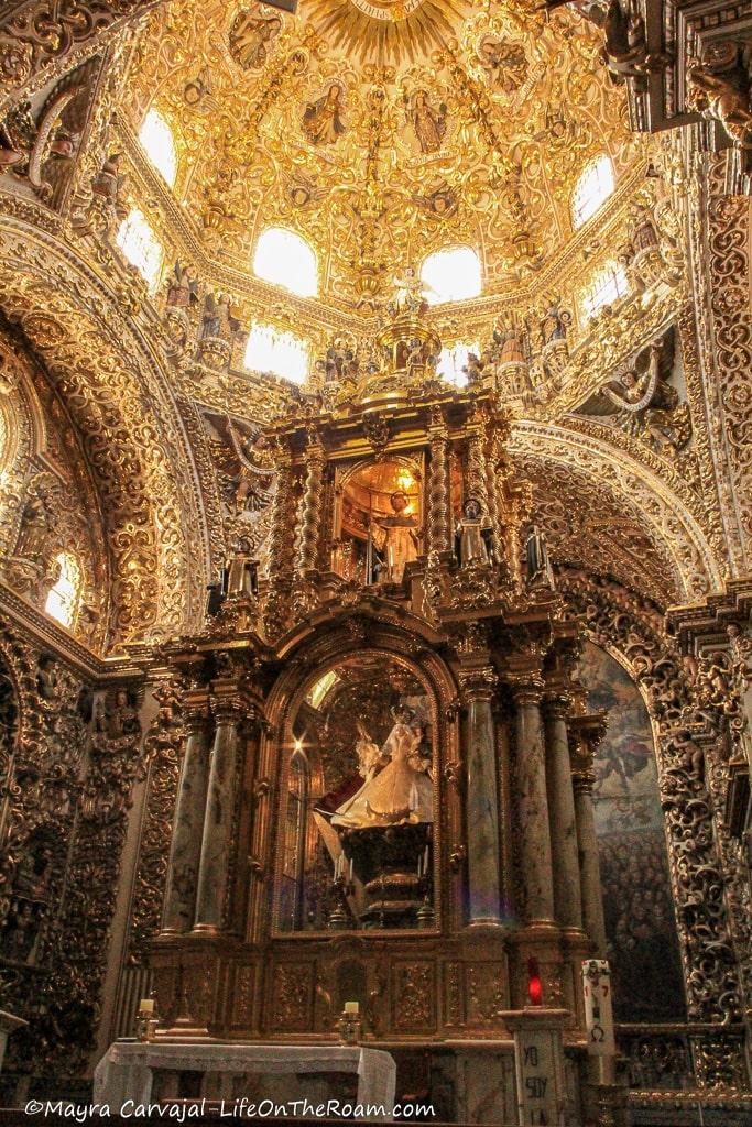 A baldaquin in a church adorned with 24 columns surrounding two statues