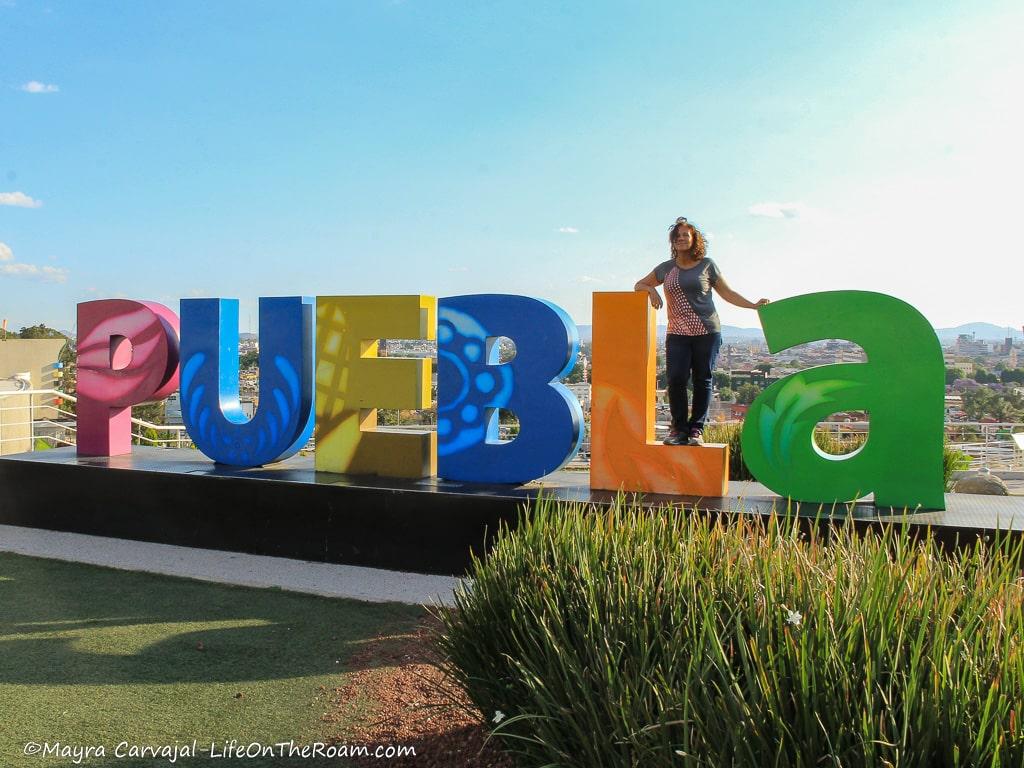 Mayra posing with the colourful "PUEBLA" sign