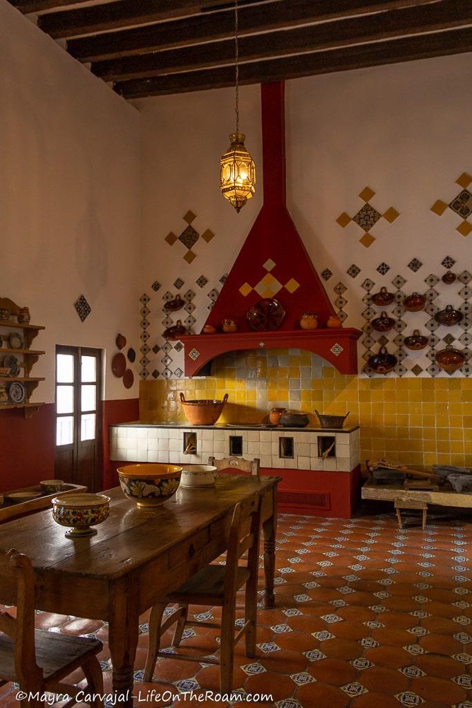 A traditional kitchen with a work table in the centre and tiled backsplash and floor