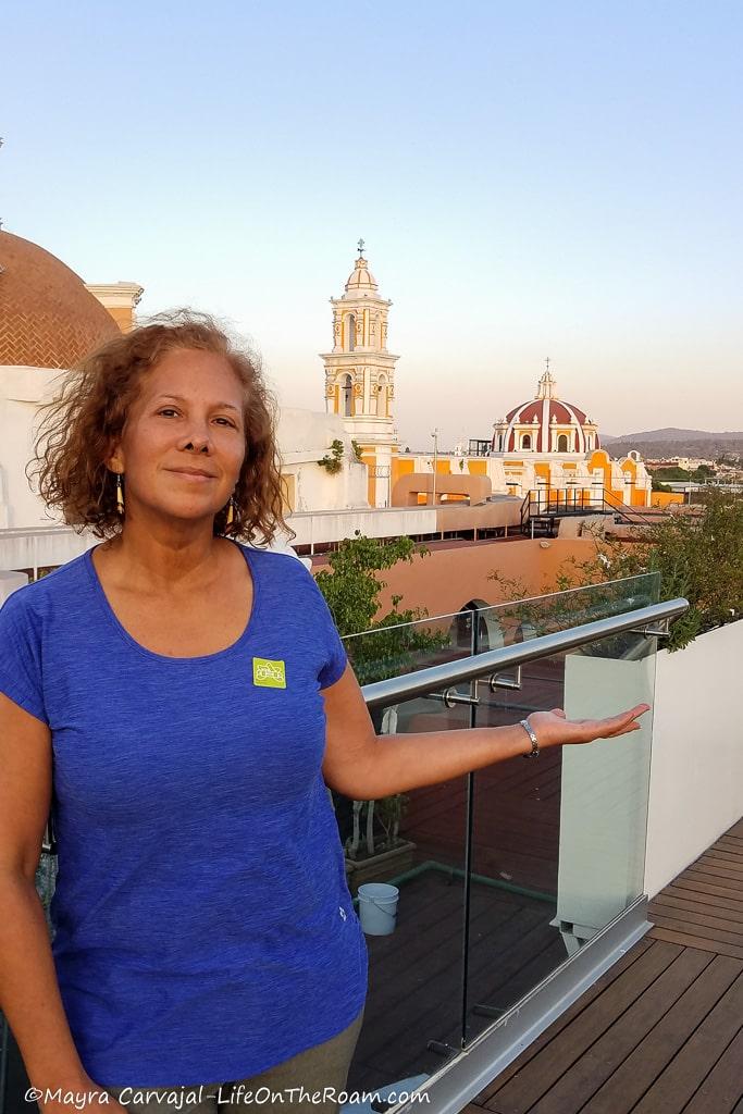 Mayra in a terrace with a city skyline with domes and towers in the background