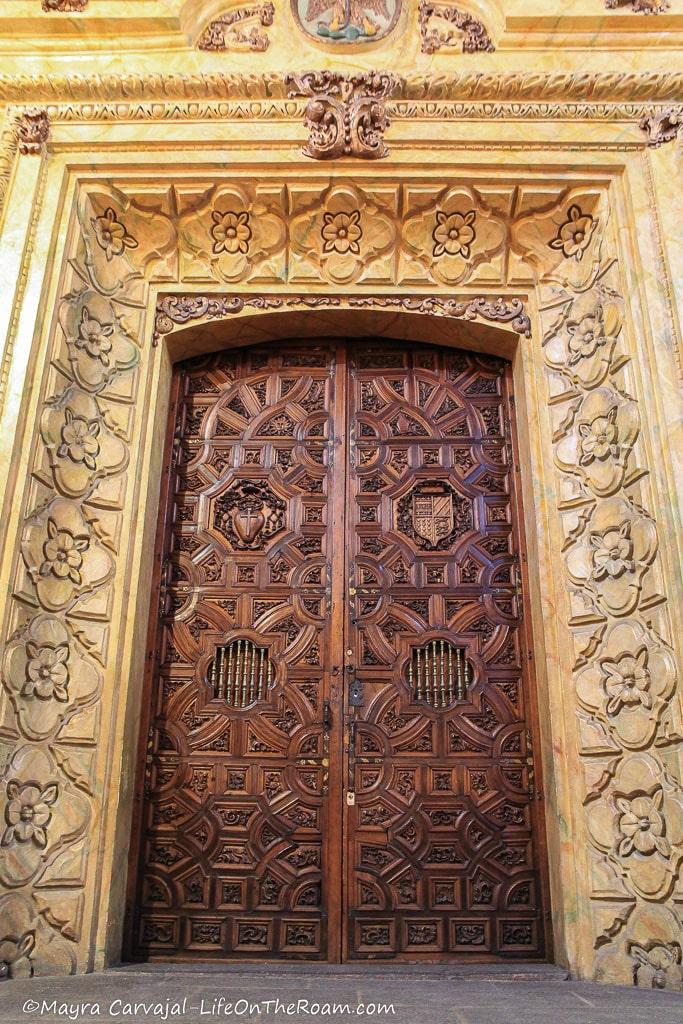 A tall door with intricate carved details and a thick stone frame