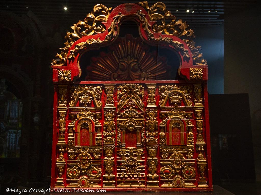 An ornate writing desk from the 18th century in red-painted wood with intricate gold details