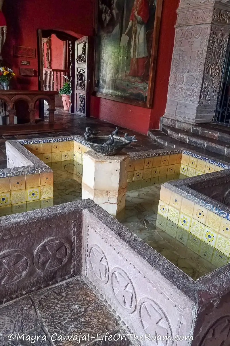 A fountain in the shape of a cross in a covered patio