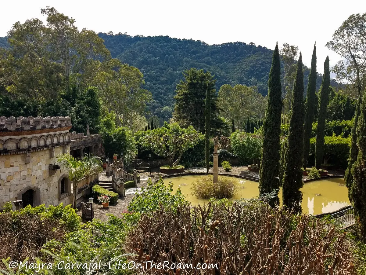 A garden with a pond and mountains in the background