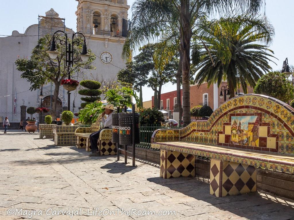 An old church in the background with a tiled bench in a square in the foreground