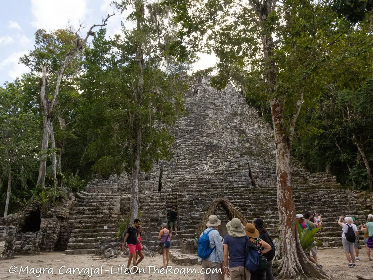 People standing in front of an old pyramid in the jungle