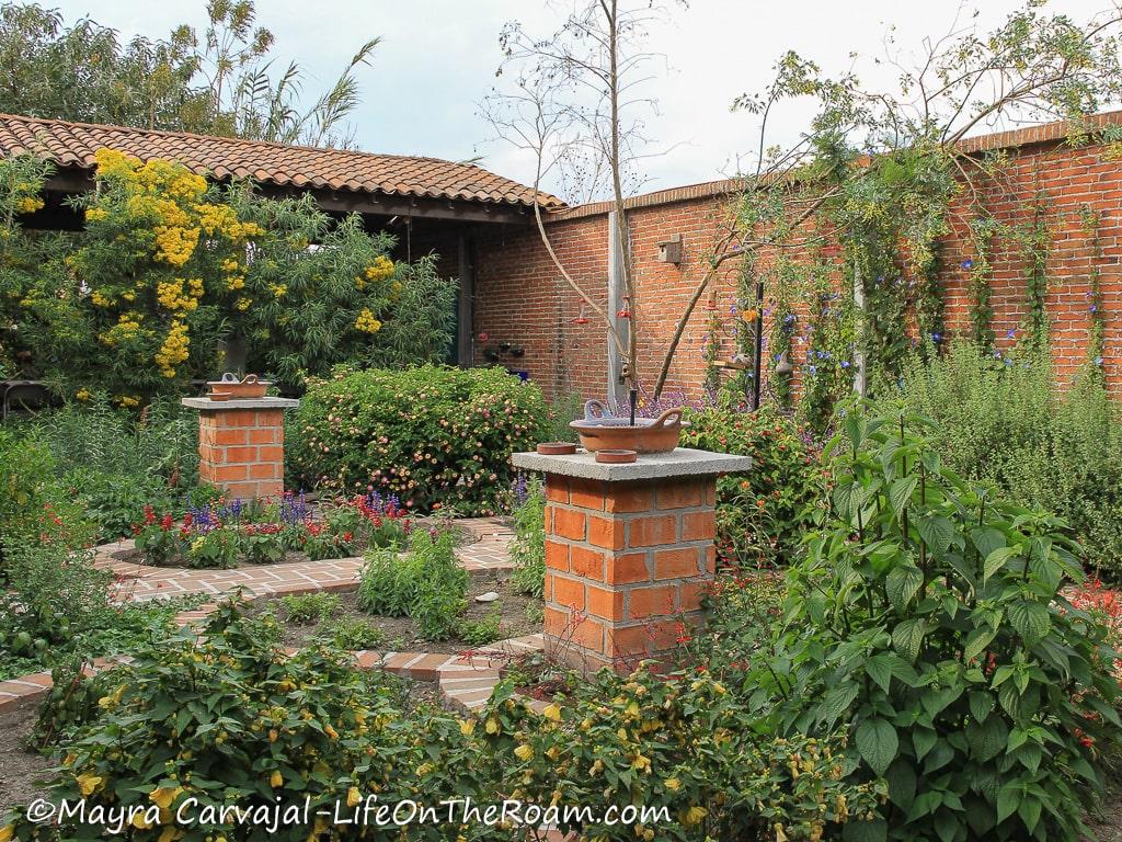 A garden with a brick wall, multicolour flowers and bird feeders