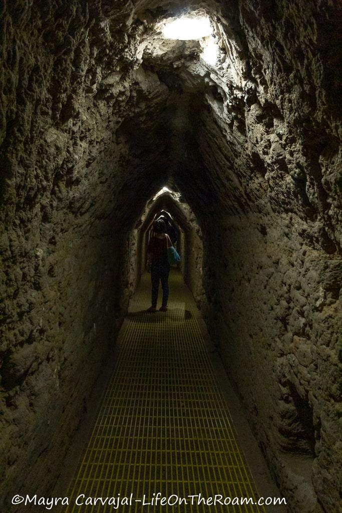 A woman in a dimly lit and narrow tunnel