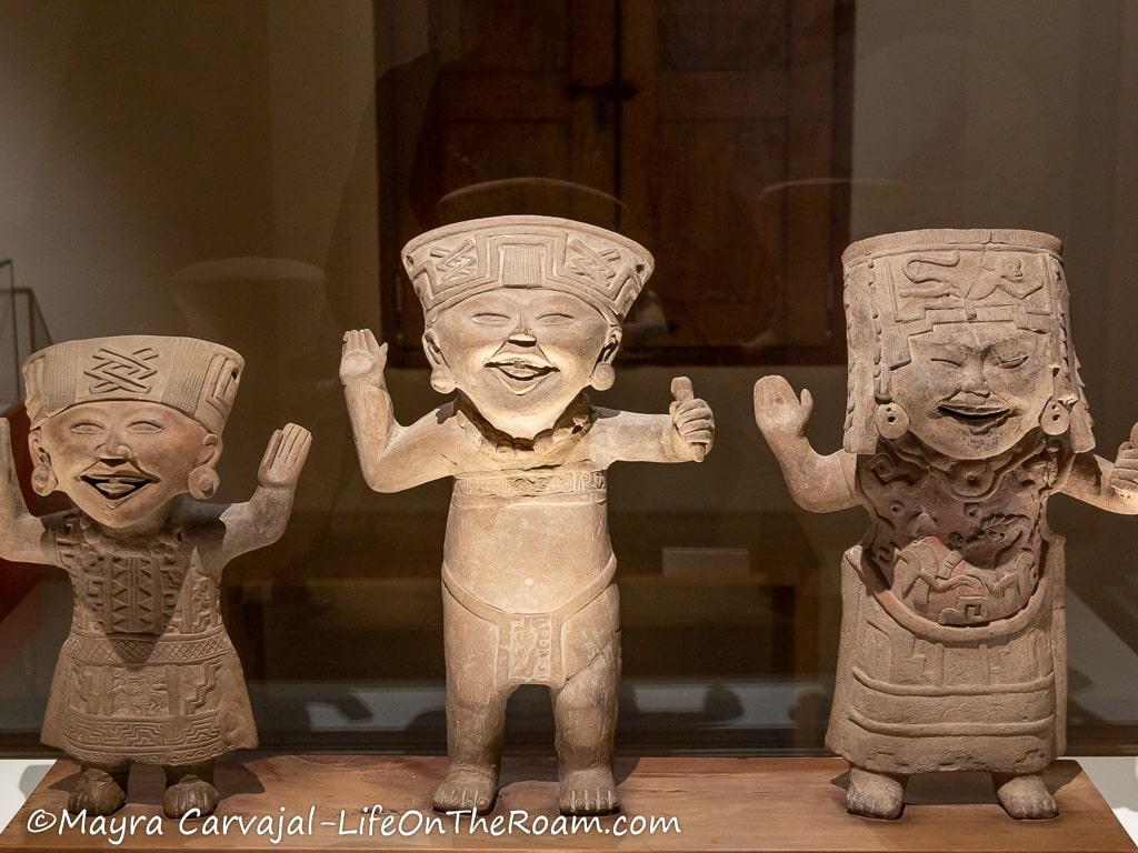 Three smiling figurines with big hats