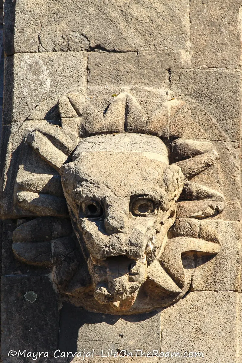 A stone ornament in a building in the form of a serpent head coming out of a flower