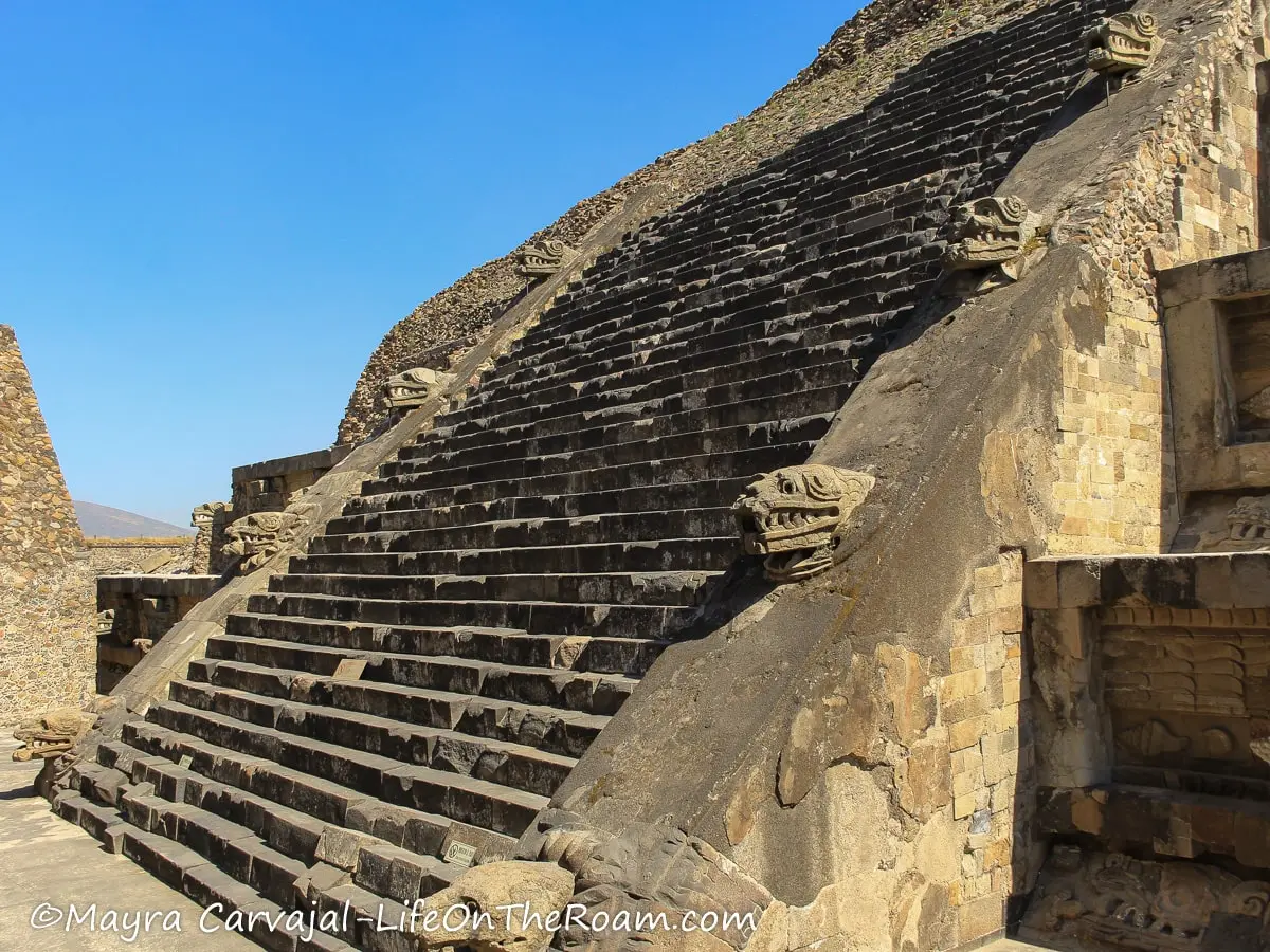 A pyramid with a staircase flanked by serpent heads in stone
