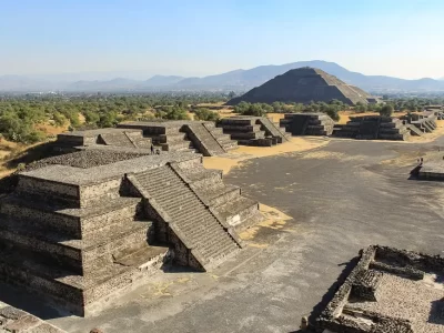 A complex of pyramids along a long walkway with mountains in the background