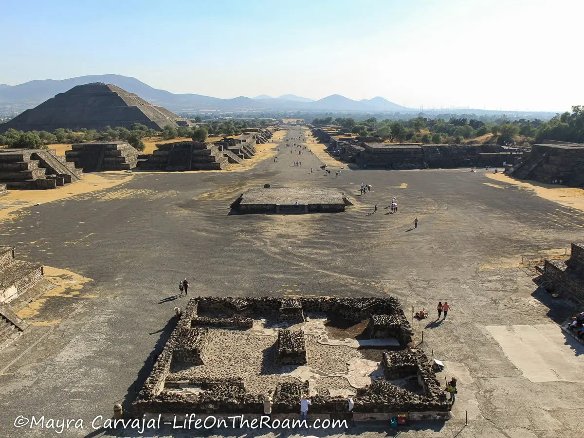 An altar in the middle of a square in a wide walkway surrounded by pyramids