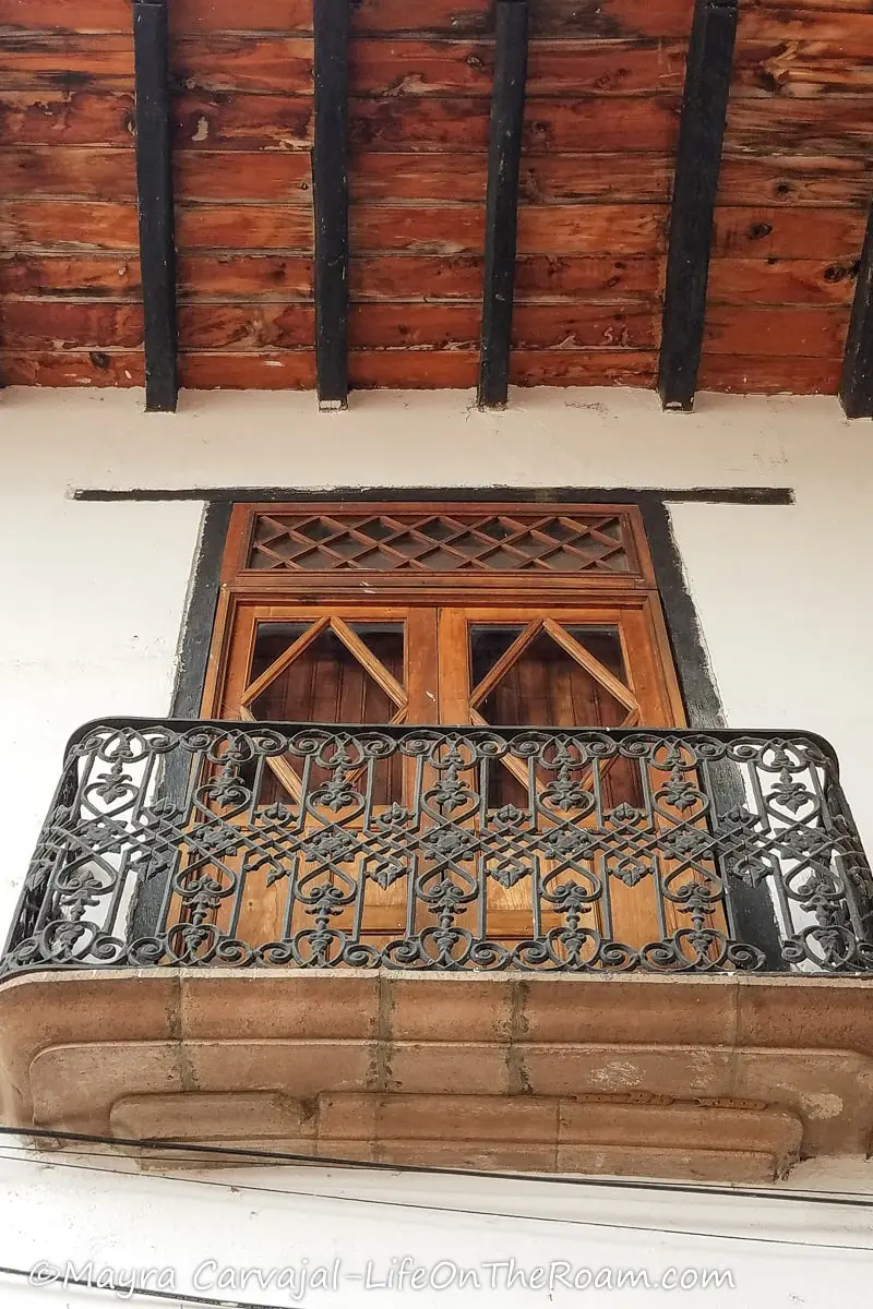A balcony in a colonial house with wrought iron front