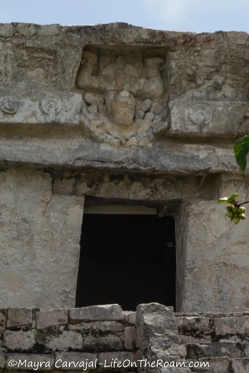 A carving on stucco above a temple door with a figure upside down
