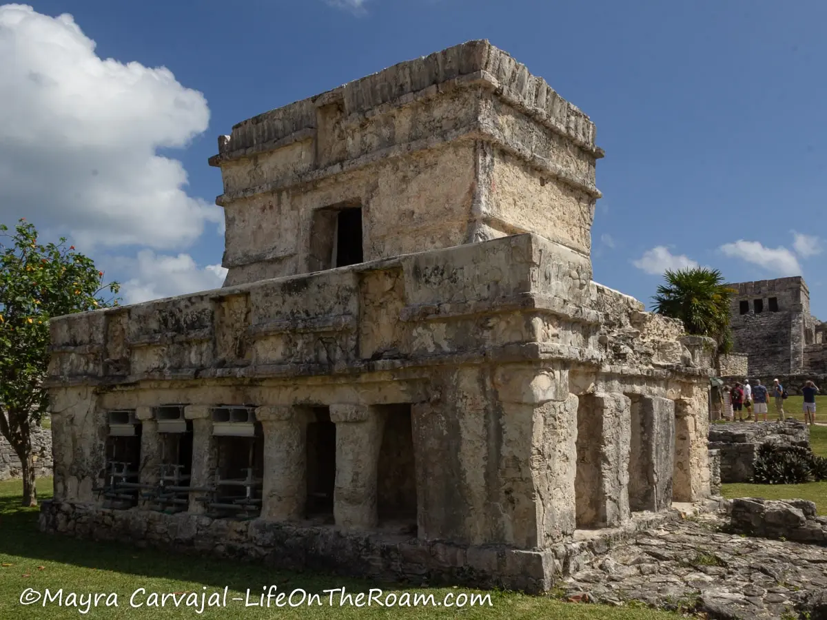 An ancient building with columns with a smaller flat-roof building on top and rests of red painting