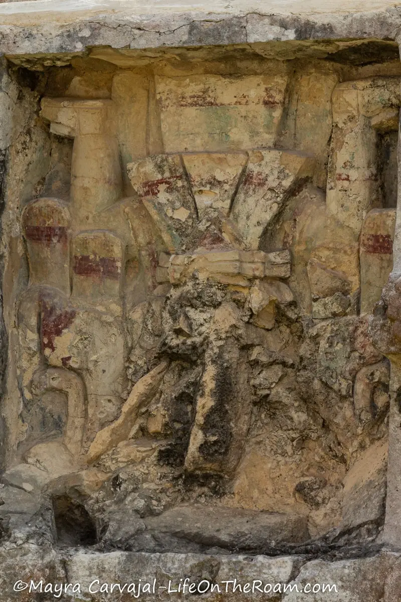 An upside figure carved in stucco with rests of red, yellow, and blue paint
