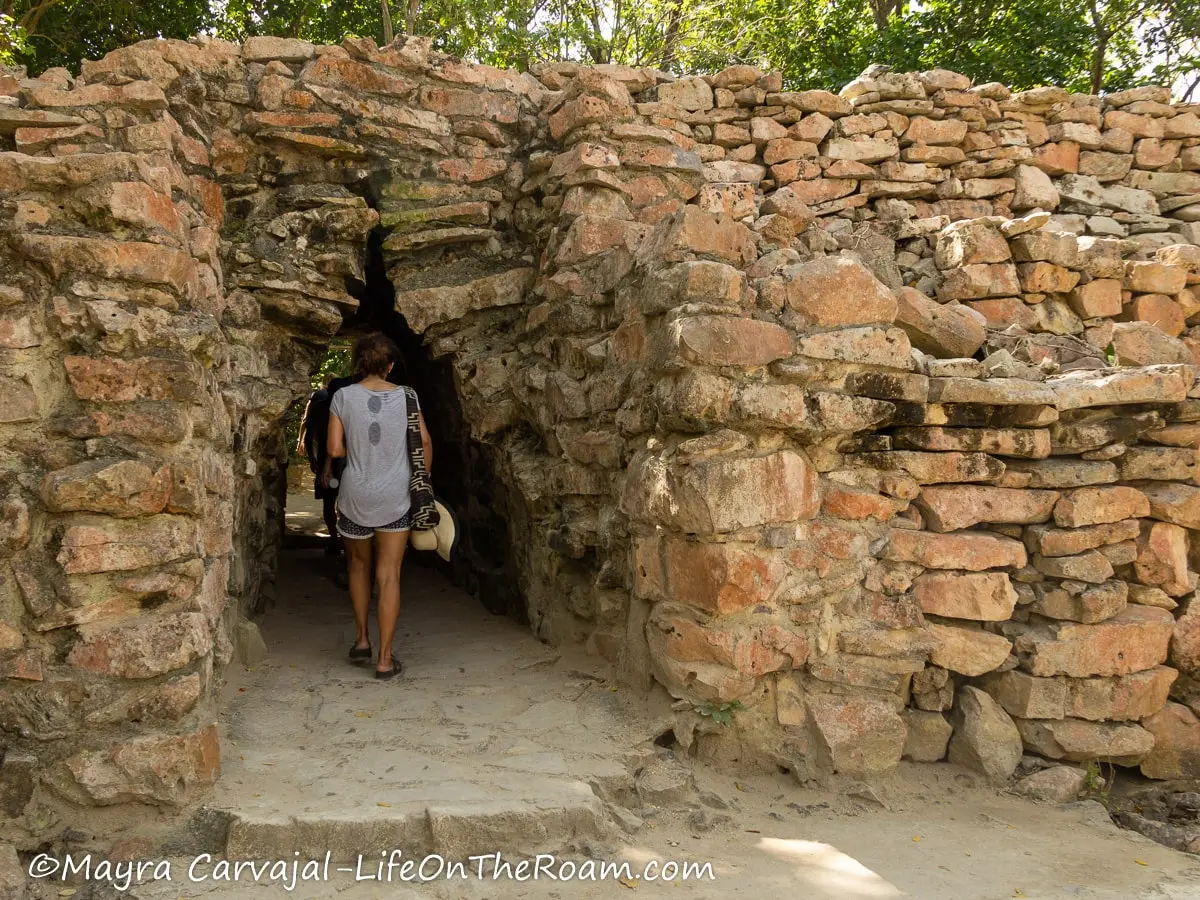 People walking through an opening on a stone wall