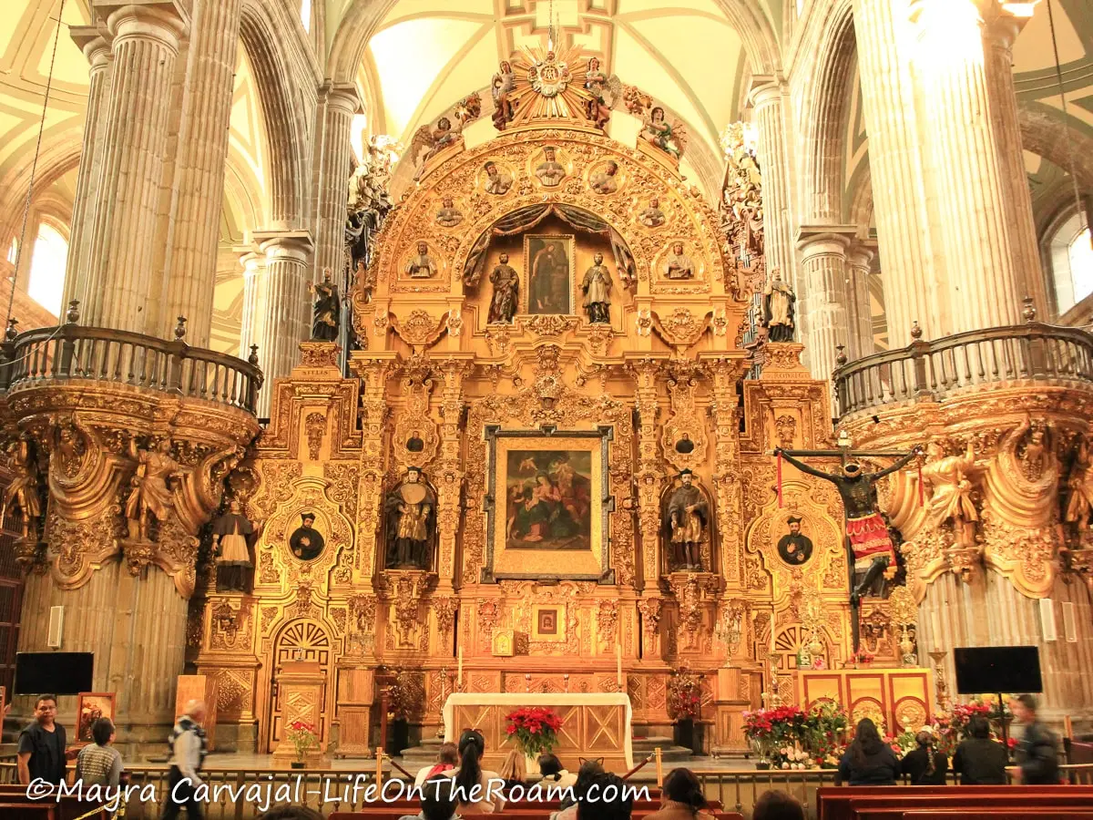 An elaborate altar covered in gold, between two columns in a cathedral