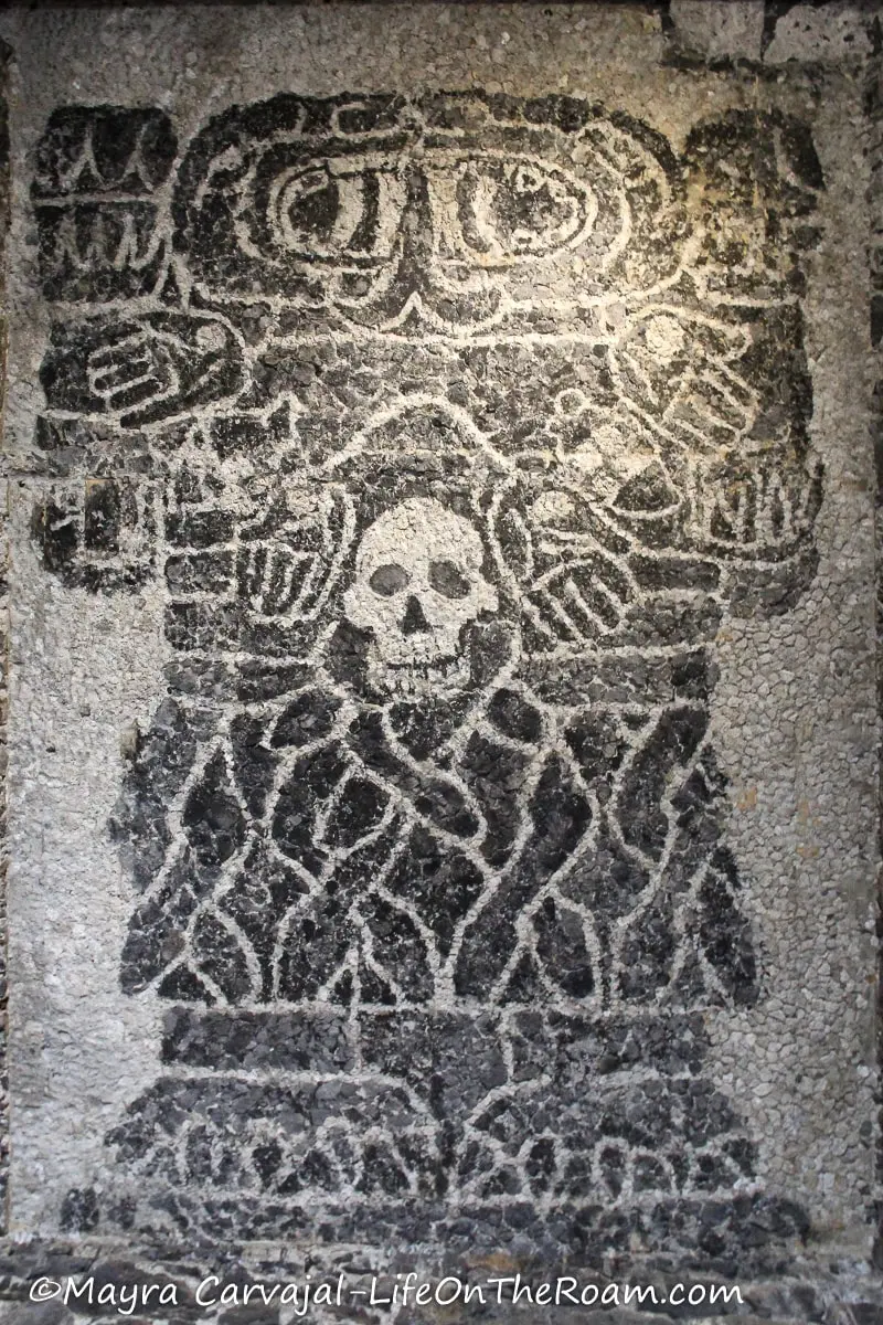 Dark  stone mosaic depicting a deity and a skull