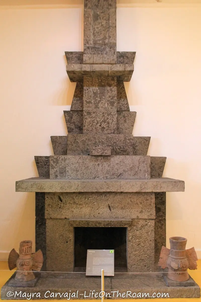 A fireplace in stone that has pre-Hispanic and Art Deco elements