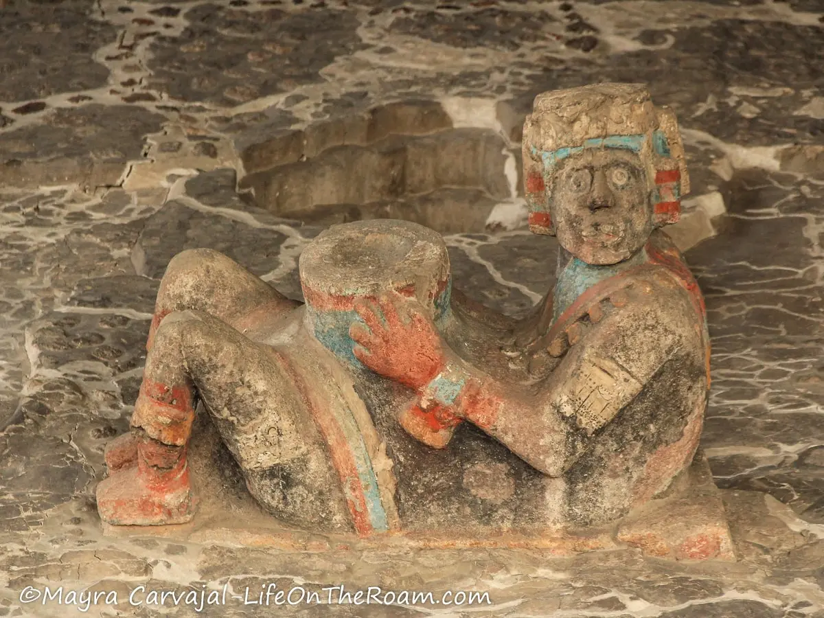 A polychrome sculpture with a man laying down and flexed knees carrying an object