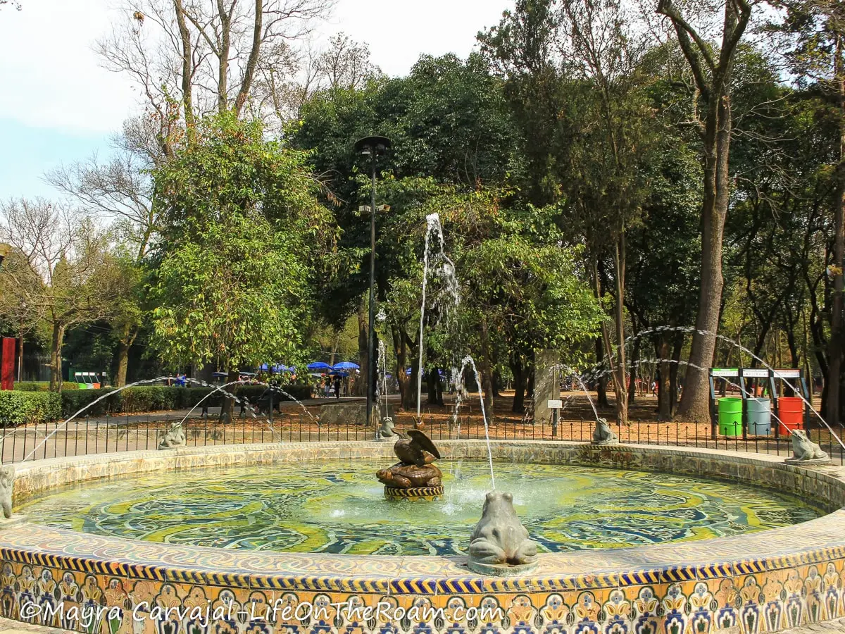 A tiled circular fountain with stone frogs
