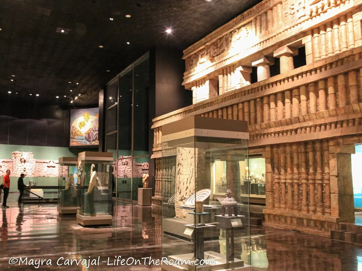 A room in a museum with a life-size reproduction of a temple and displays with artifacts