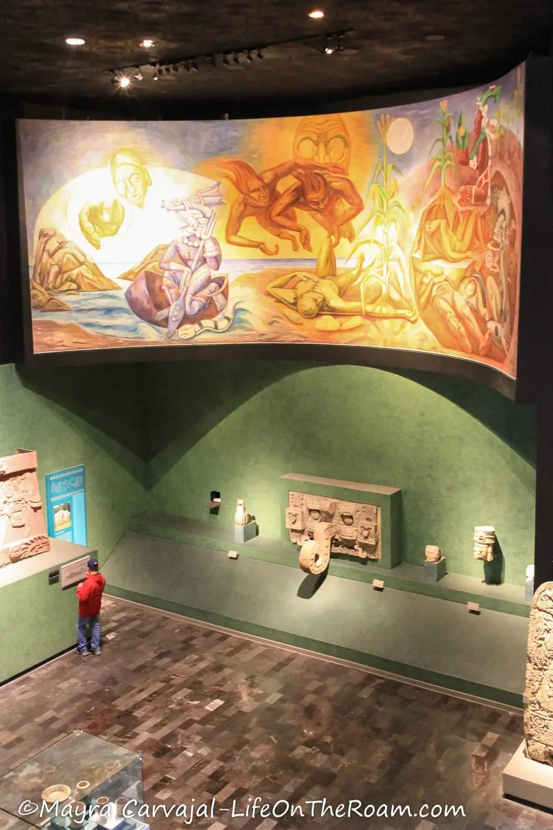 A museum with ancient artifacts and a mural