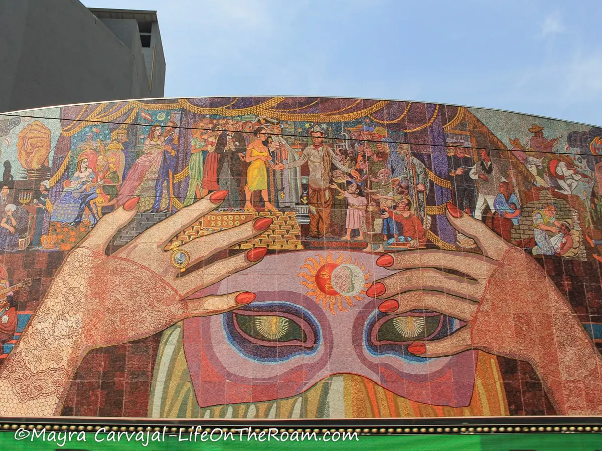 A mural above a theatre entrance featuring a masked woman and historic figures