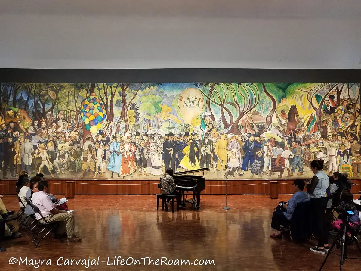 A colourful large mural in a hall with a piano