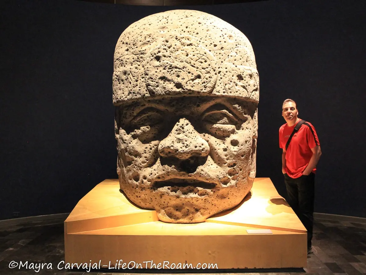 Man standing next to a monumental stone head