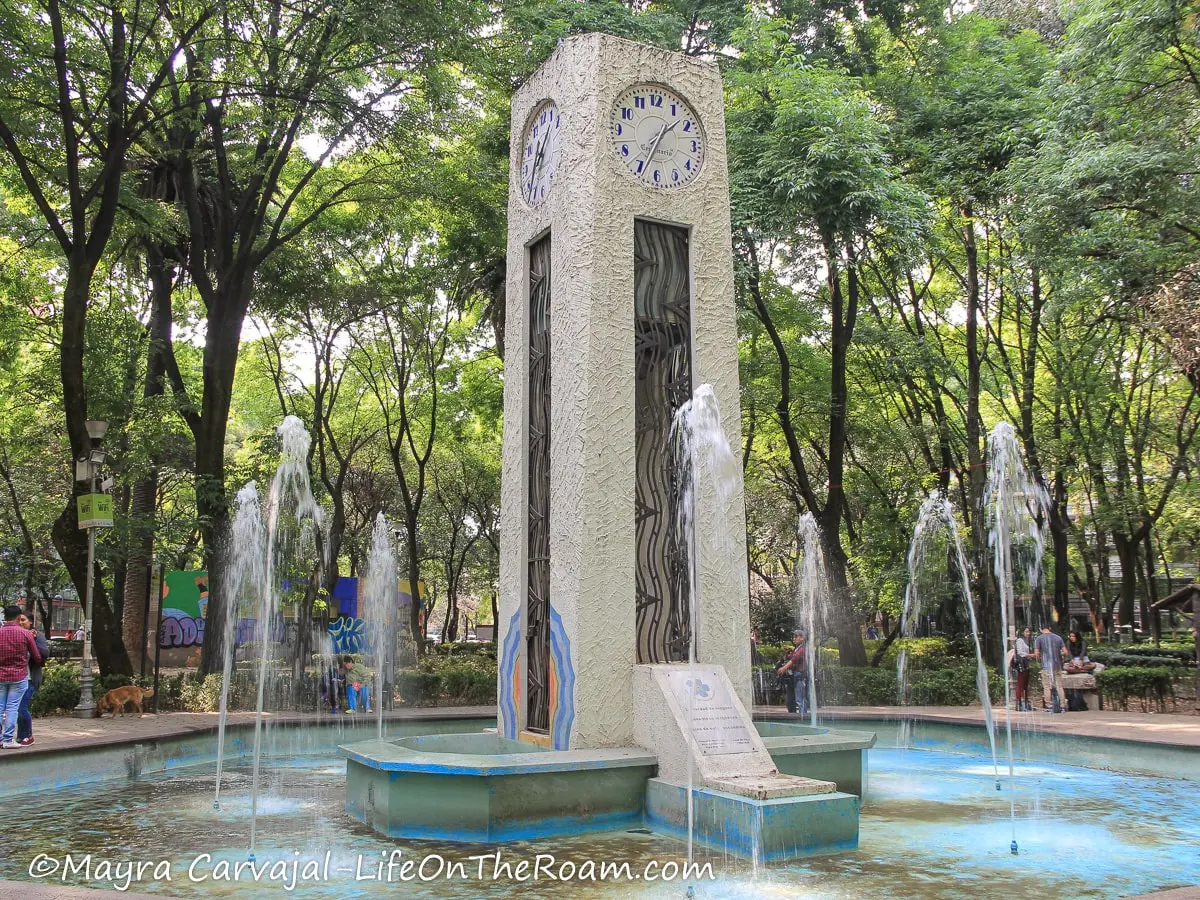 A fountain in an urban park with an Art-Déco clock in the centre