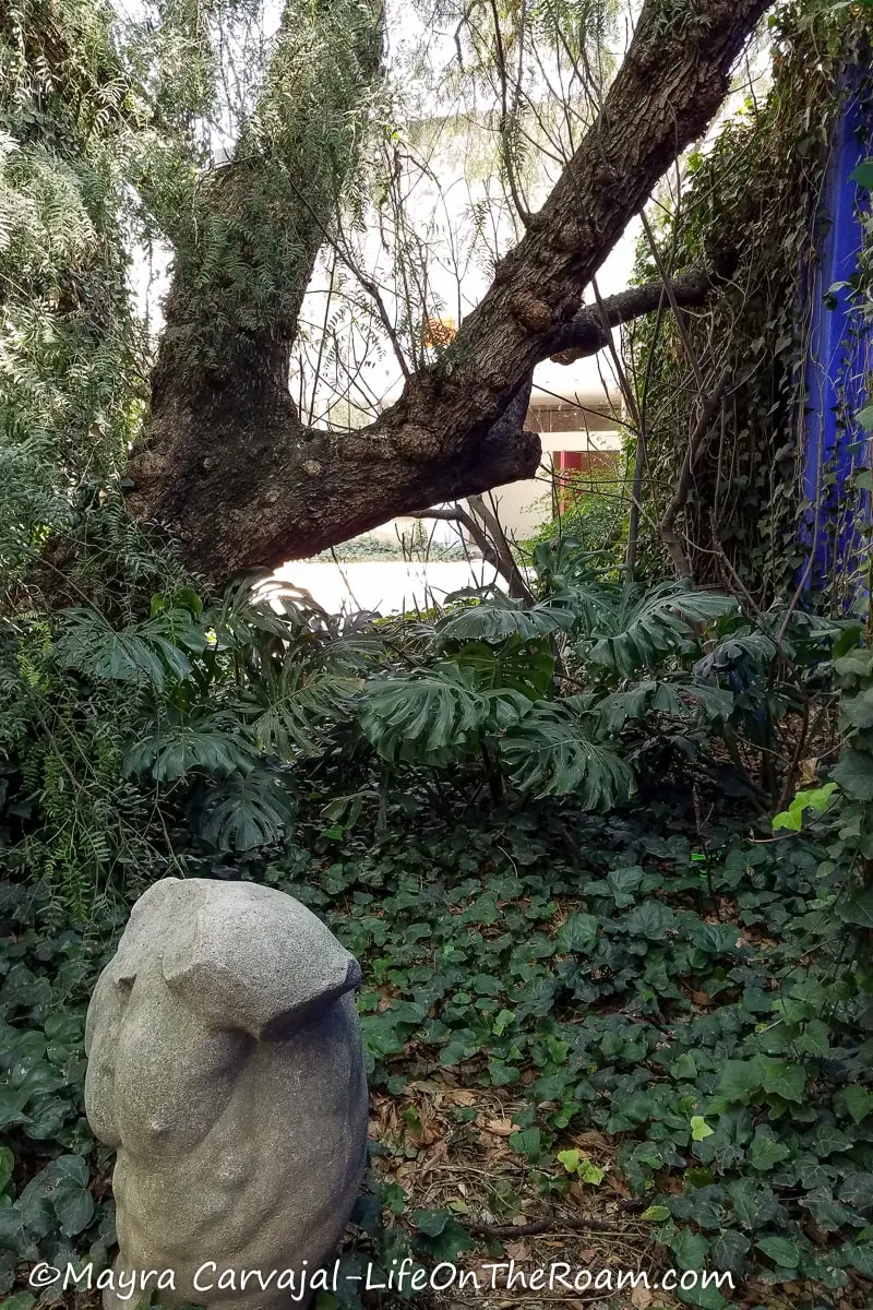 A stone sculpture of a torso in a garden
