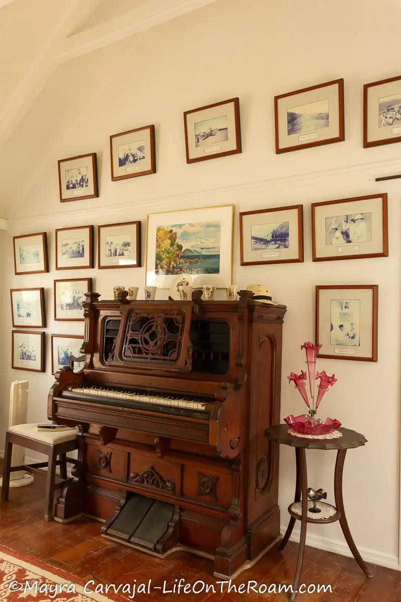 An antique organ against a wall with a collection of old photographs