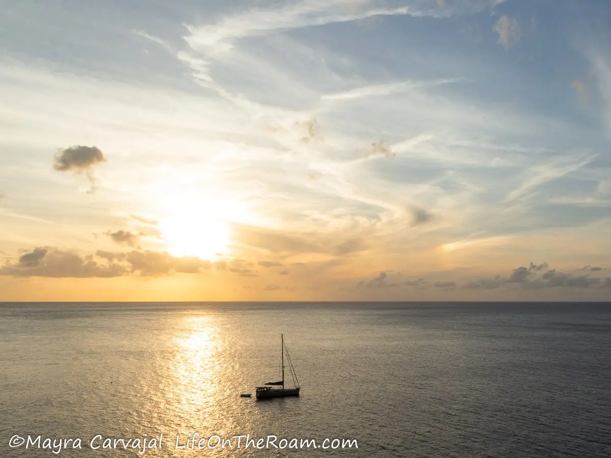 A sunset over the sea with a boat sailing 
